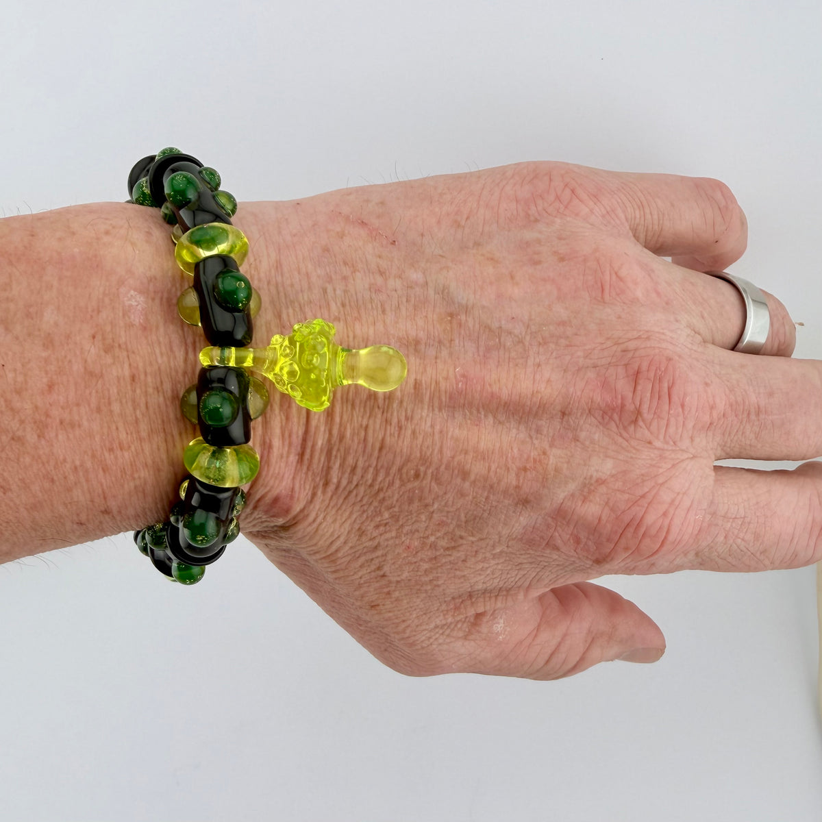 Stretchy Black Glass Bracelet with Green dots that Glow Bright Under Black Light - JeffBeckerGlass.com